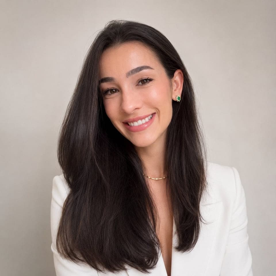 Retrato da Dra. Eduarda Mageski, de blazer branco sobre fundo claro, cabelo solto, sorrindo para a câmera.